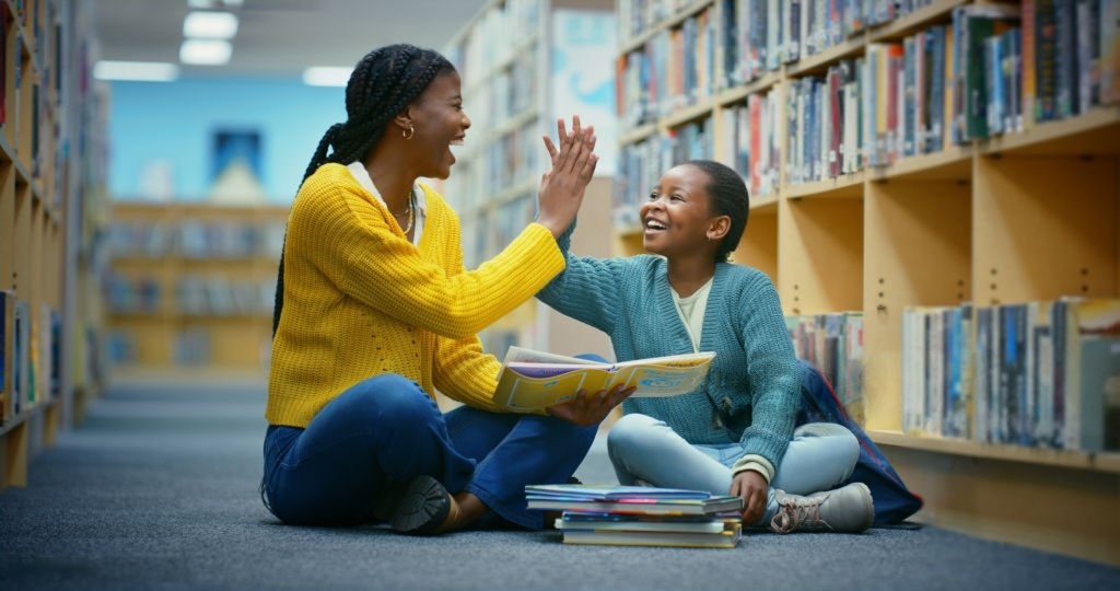 Une bibliothécaire et une élève partageant un livre en bibliothèque